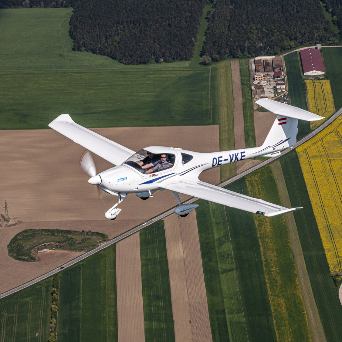 Diamond DA20 training aircraft flying over agricultural fields

