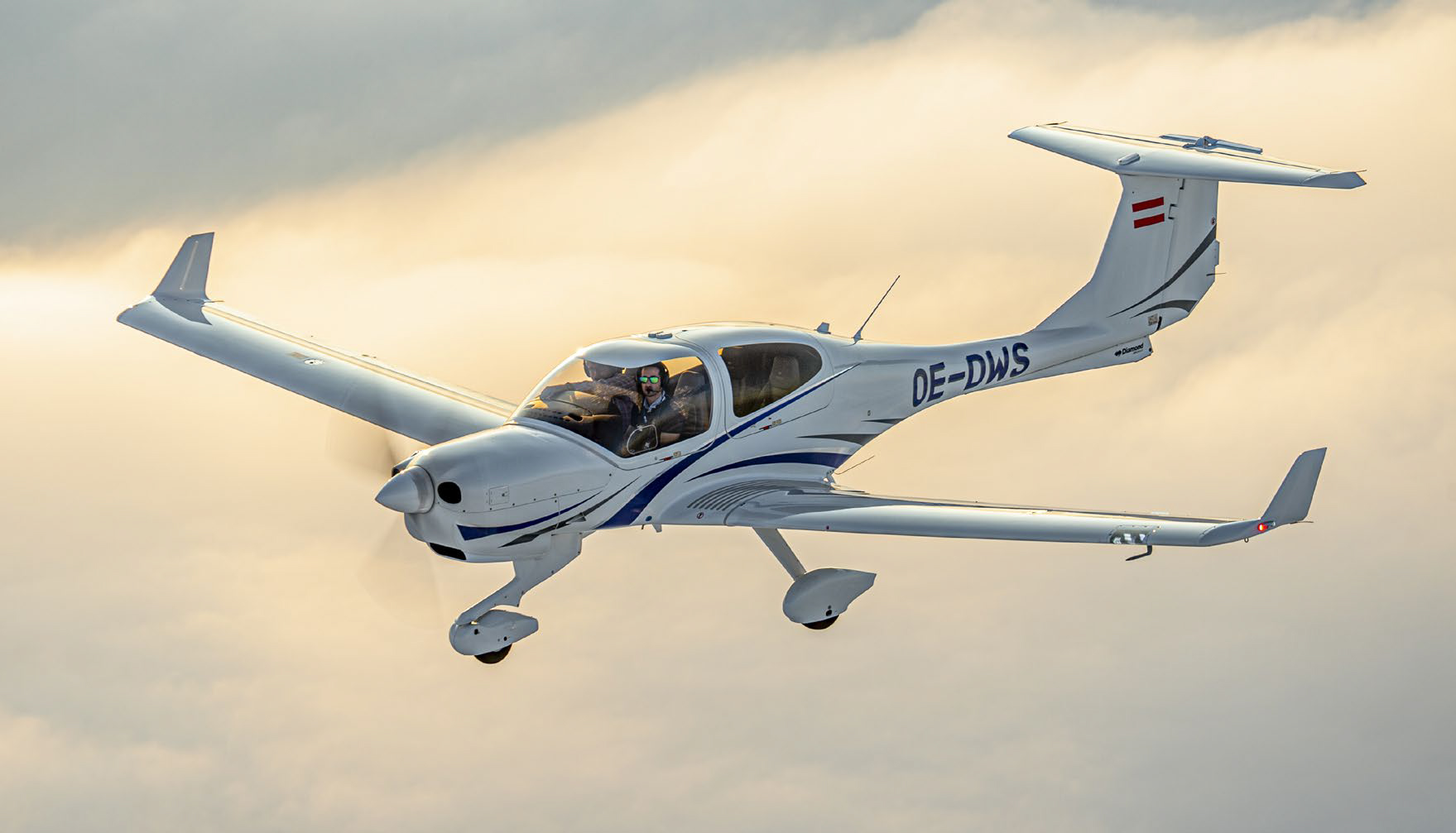 Diamond DA40 single‑engine training aircraft in flight against a cloudy sky

