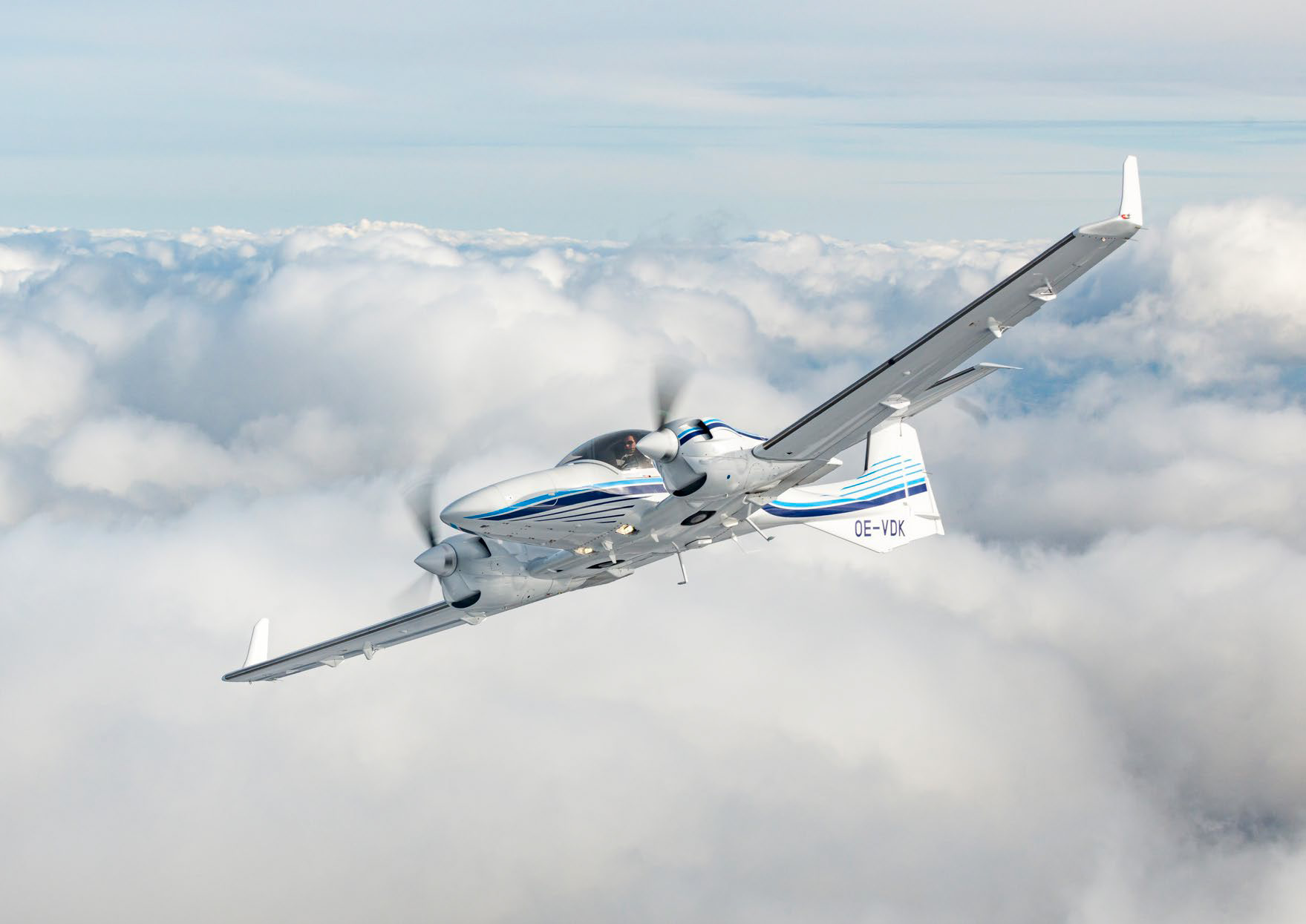 Diamond DA42 multi‑engine training aircraft flying above cloud layer

