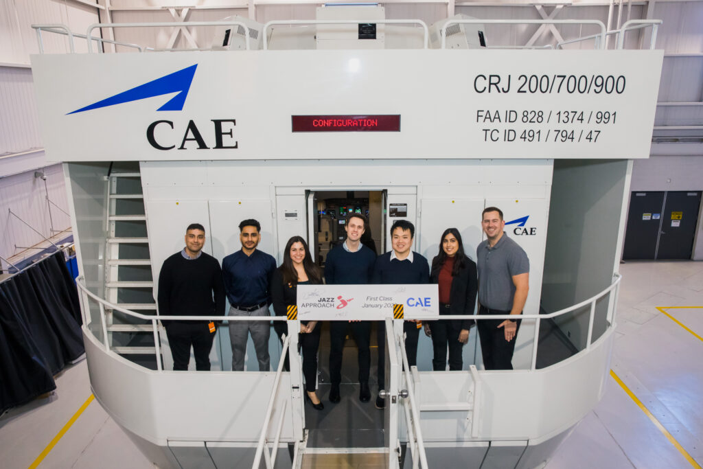 Trainees standing inside a CAE flight simulator training facility

