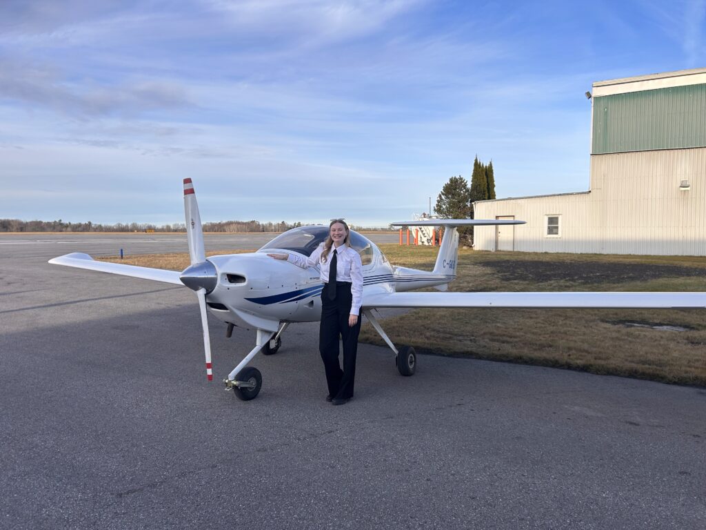 Pilot trainee standing beside a small training aircraft on the airport tarmac

