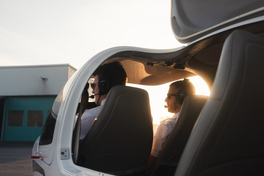 Flight trainees seated inside a small aircraft cockpit during pre‑flight preparation